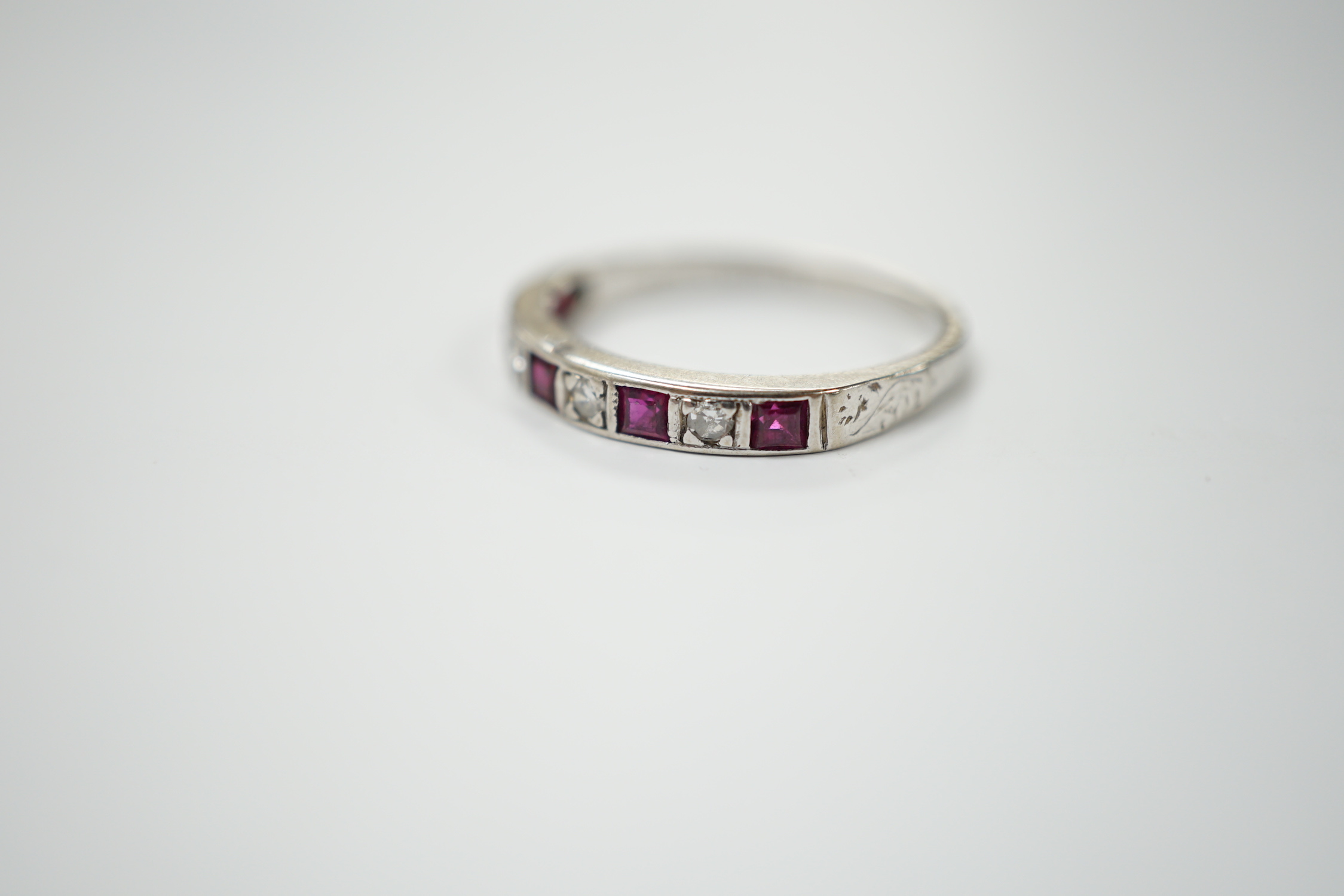 A modern 18ct white gold, ruby and diamond set half eternity ring, size O, gross weight 2.7 grams.